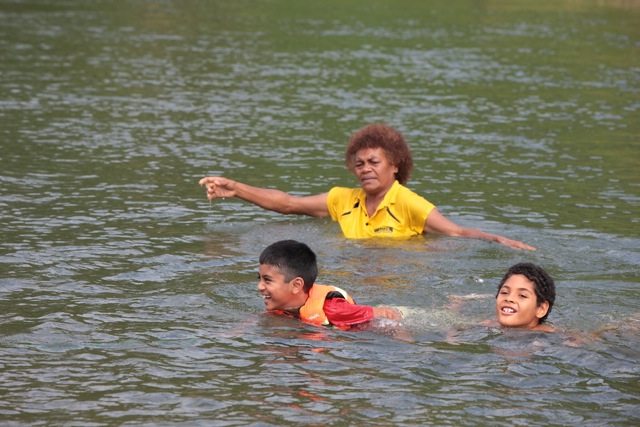 Teacher overseeing two pupils in the current of a river.